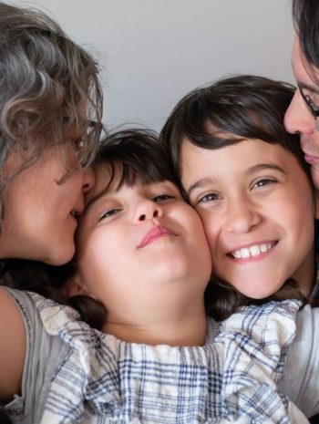 A joyful family of four sharing a warm embrace, highlighting love and togetherness indoors.