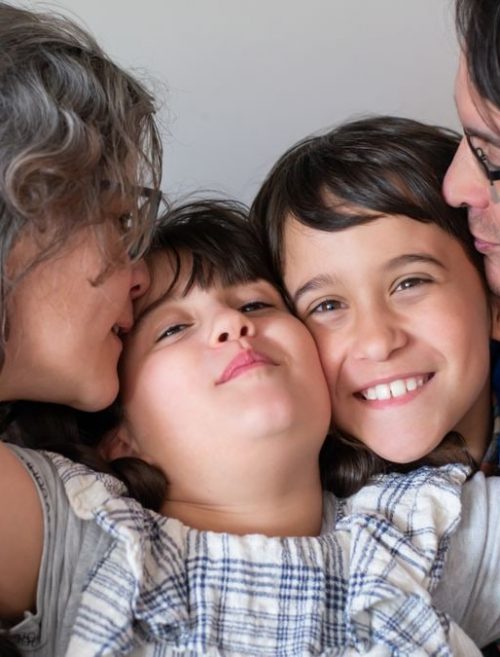 A joyful family of four sharing a warm embrace, highlighting love and togetherness indoors.